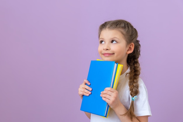 Une petite fille en nattes et un livre dans ses mains sur fond violet