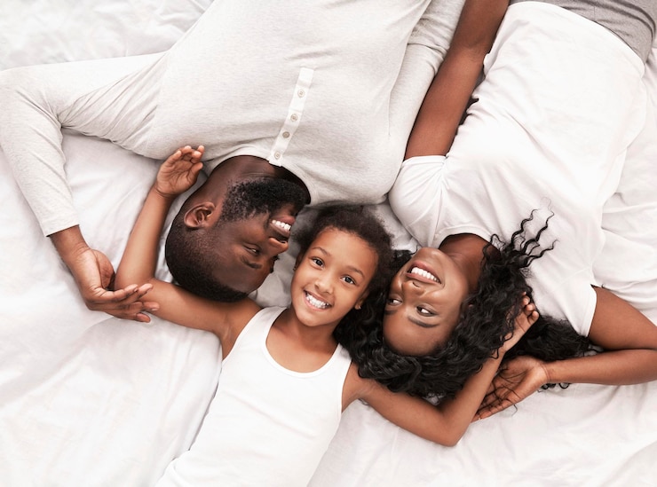 Photo une petite fille noire et ses parents allongés ensemble sur le lit.