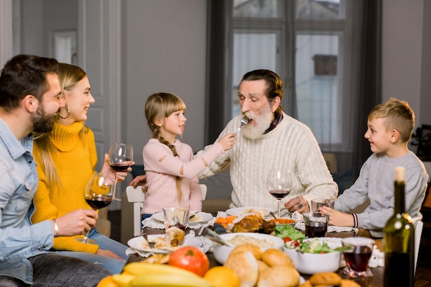 Petite fille nourrit son vieux grand-père et lui donne de délicieuses pâtes, souriant et riant