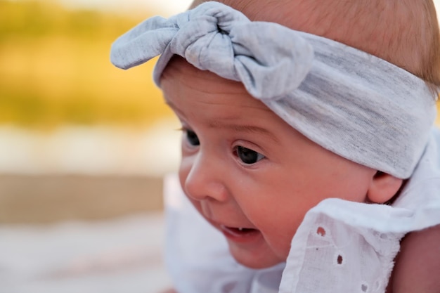 La petite fille nouveau-née se trouve sur la plage dans une robe blanche