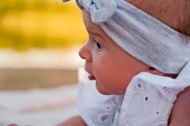 La petite fille nouveau-née se trouve sur la plage dans une robe blanche