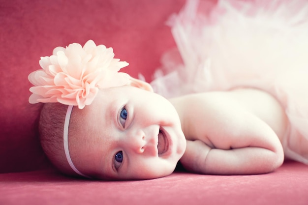 Petite fille nouveau-née souriante avec une fleur dans les cheveux