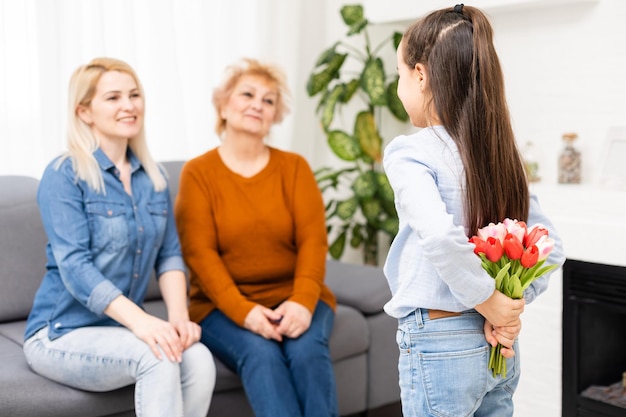 Une petite fille offre un bouquet de tulipes à sa maman et sa grand-mère. Ils célèbrent la fête des mères. Ils ont des vacances familiales traditionnelles.