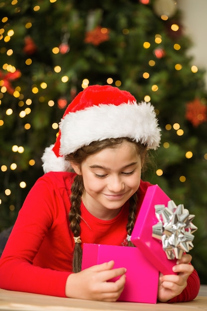 Petite fille ouvrant un cadeau à Noël à la maison dans le salon