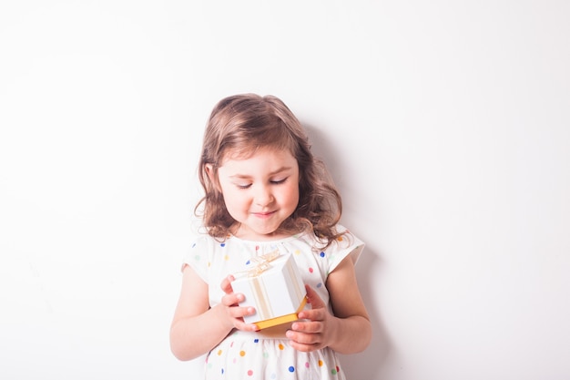 Une petite fille ouvre une boîte cadeau avec un cadeau. Moment heureux pour le petit bambin