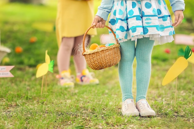 Petite fille avec panier d'oeufs colorés dans le concept de chasse de Pâques parc
