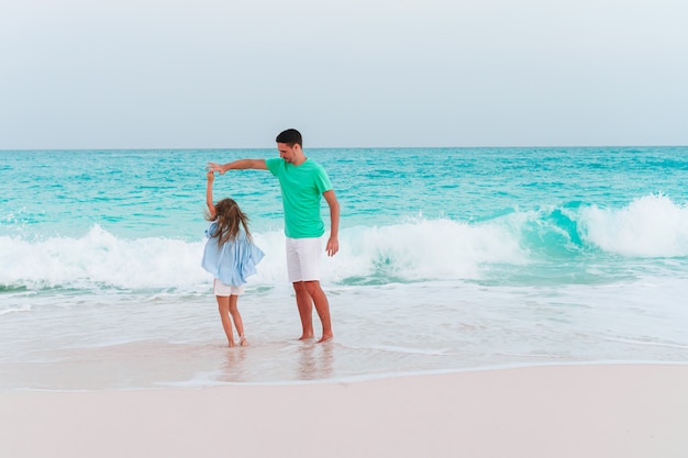 Petite fille et papa heureux s'amuser pendant les vacances à la plage