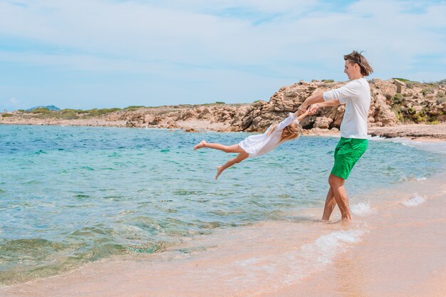 Petite fille et papa heureux s'amuser pendant les vacances à la plage