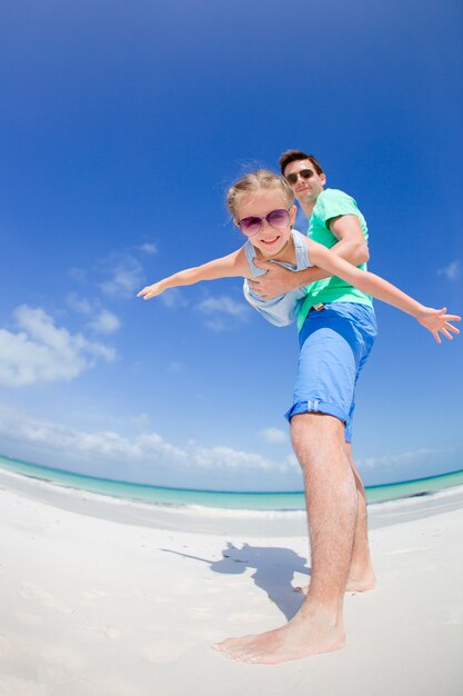 Petite fille et papa heureux s'amuser pendant les vacances à la plage