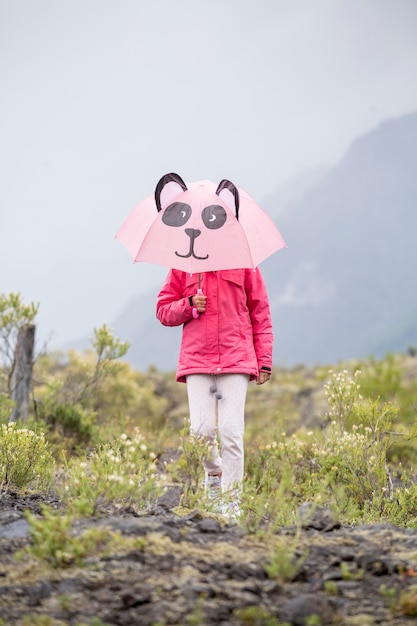 Petite fille avec un parapluie panda marchant dans la montagne