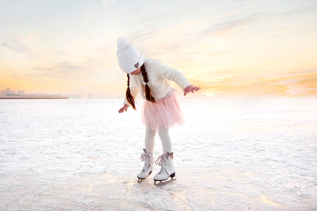 Petite fille patinage sur glace dans la lumière du coucher du soleil du soir