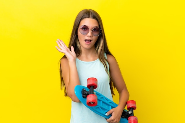 Petite fille de patineuse caucasienne isolée sur fond jaune avec un patin et faisant un geste de surprise