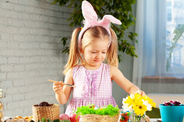 Petite fille peignant des oeufs pour Pâques à la maison