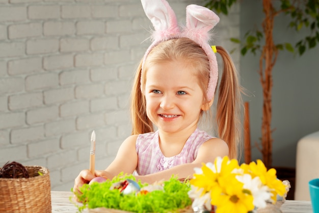 Petite fille peignant des oeufs pour Pâques à la maison