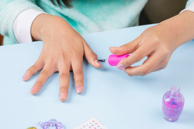 Petite fille peignant ses ongles à la maison avec du vernis transparent