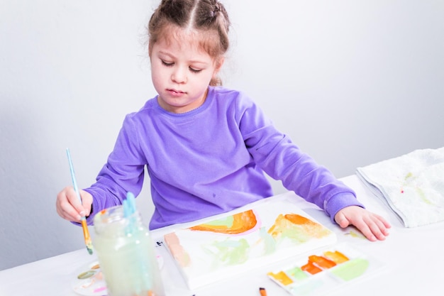 Petite fille peignant sur toile avec de la peinture acrylique.