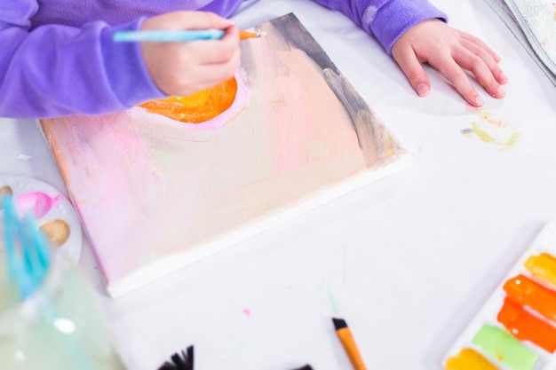 Petite fille peignant sur toile avec de la peinture acrylique.