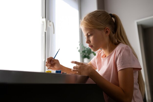 Petite fille peignant un vase à la maison