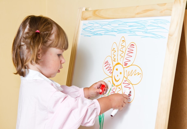 Petite fille peindre sur un tableau avec un marqueur