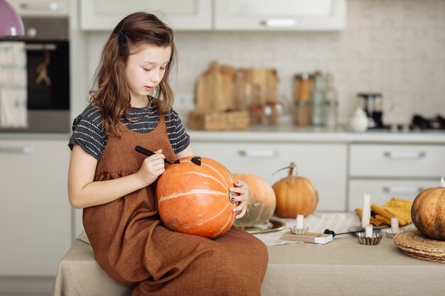 Petite fille peint une citrouille pour Halloween