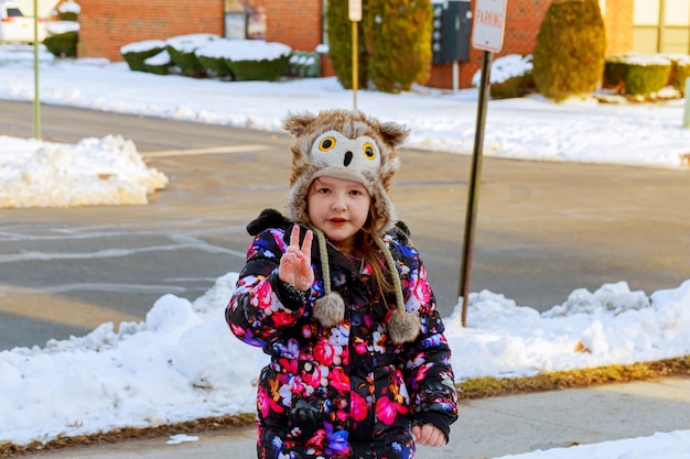 Petite fille pelleter la neige sur le chemin de la maison. Beau jardin enneigé ou cour avant.