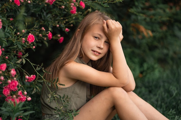 Petite fille pensive à l'extérieur assis près d'un rosier