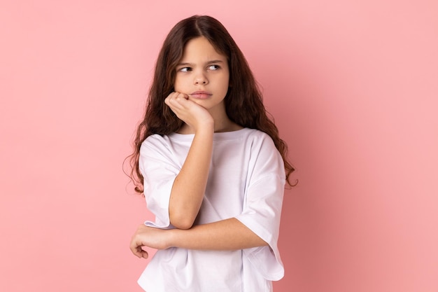 Petite fille pensive réfléchie pensant à l'avenir tenant le menton ayant une expression faciale sérieuse