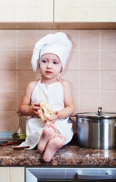 petite fille pétrissant la pâte dans la cuisine