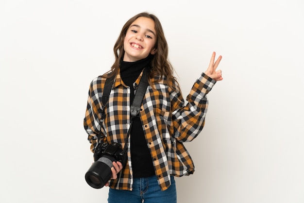 Petite fille photographe isolée sur le mur souriant et montrant le signe de la victoire