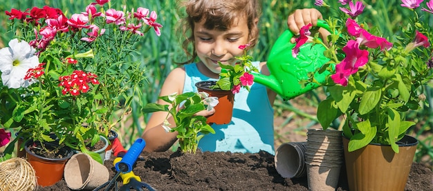 Une petite fille plante des fleurs.