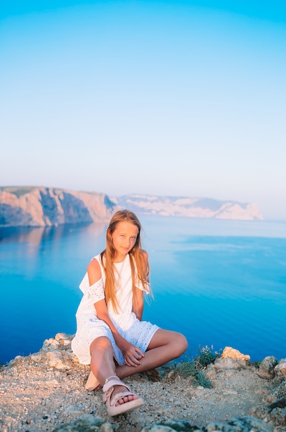 Petite fille en plein air sur le bord de la falaise profiter de la vue sur le rocher du sommet de la montagne