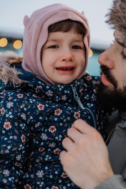 Une petite fille pleure dans les bras de son père dans la rue dans le froid gelée et voulant rentrer chez elle