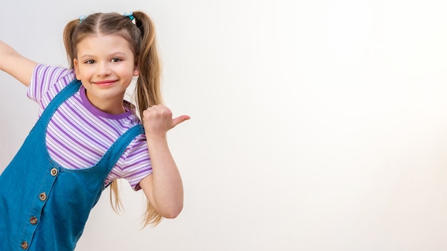 Une petite fille pointe la main vers la publicité. Fond isolé blanc.