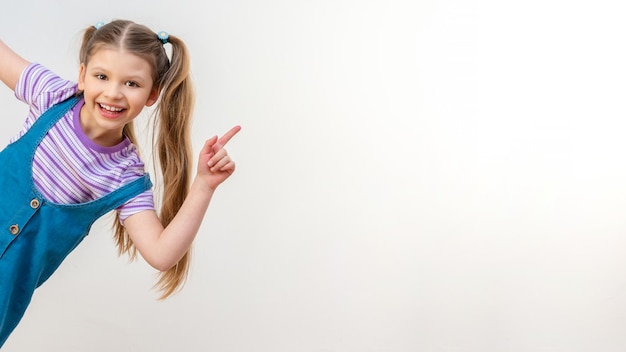 Une petite fille pointe la main vers la publicité. Fond isolé blanc.