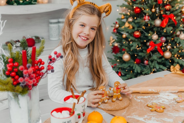 Petite fille portant un bonnet de noel préparant des biscuits de Noël dans la cuisine à la maison.