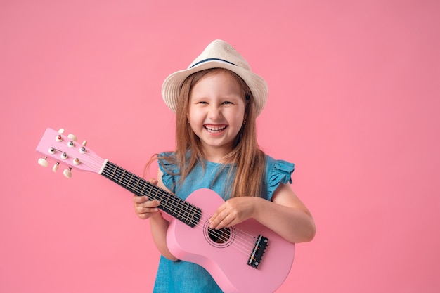 Petite fille portant un chapeau et une guitare ukulélé