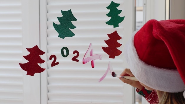 Photo une petite fille portant un costume rouge de chapeau de père noël décore la fête du nouvel an de la maison de vacances d'hiver.