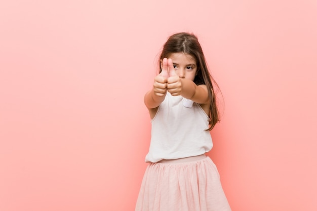 Petite fille portant un look de princesse avec des pouces vers le haut, des acclamations pour quelque chose, un soutien et un concept de respect.