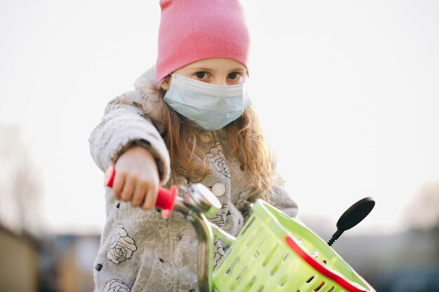 Petite fille portant un masque médical pendant l'épidémie de coronavirus. Petite fille malade portant une protection pendant la pandémie. Jolie jeune fille de race blanche prenant un masque médical en plein air