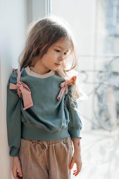 Petite fille porte des ailes roses une couronne une baguette magique et s'imagine une fée magique et joue à des jeux imaginaires à la maison