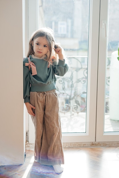 Petite fille porte des ailes roses une couronne une baguette magique et s'imagine une fée magique et joue à des jeux imaginaires à la maison