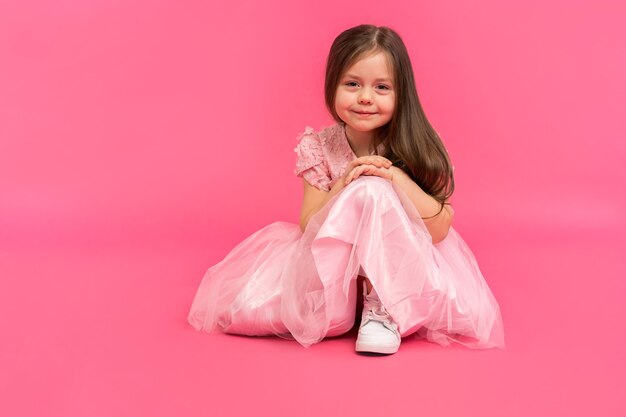 Petite fille, portrait en studio d'un bel enfant en robe rose sur fond rose.