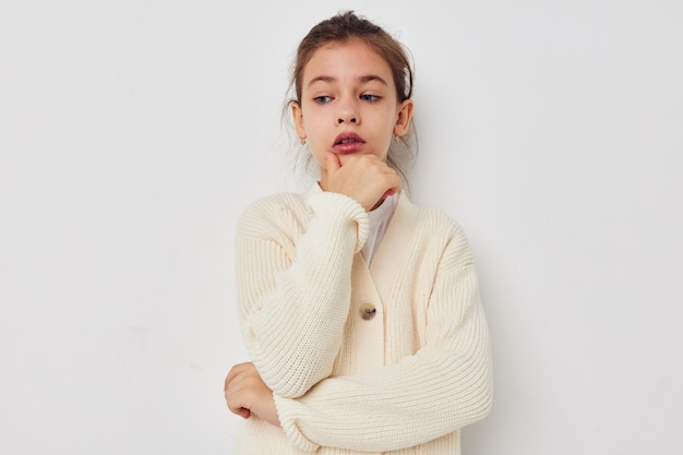 Petite fille posant dans un pull blanc fond clair