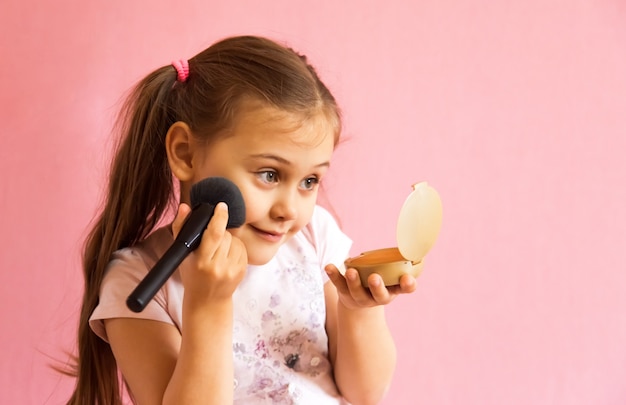 Photo petite fille poudrant son visage et regardant dans le miroir