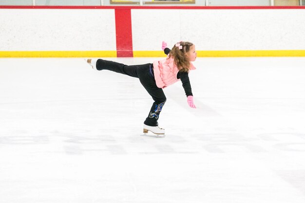 Petite Fille Pratiquant Le Patinage Artistique Se Déplace Sur La Patinoire Intérieure.