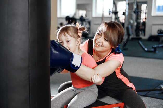 petite fille pratique la boxe, fille enseigne maman à la boîte, drôle mère et fille dans le gymnase, heureuse mère et fille dans le gymnase rôle de genre émotionnel masculin