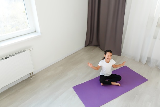 petite fille pratique le yoga à la maison