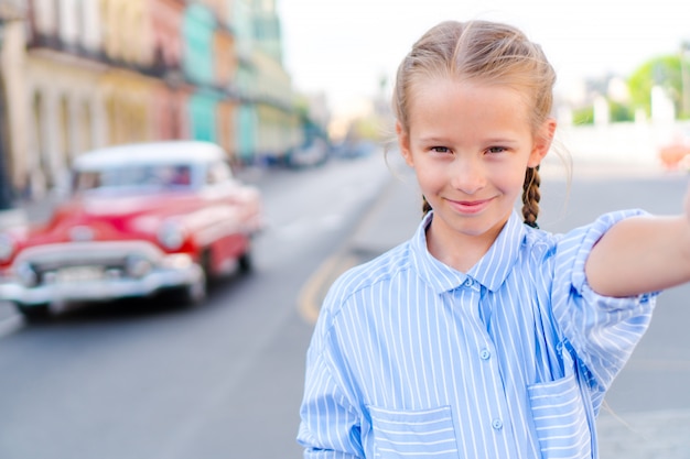 Petite fille prenant selfie dans un quartier populaire de la vieille Havane, à Cuba. Portrait d'enfant à l'extérieur dans une rue de la Havane