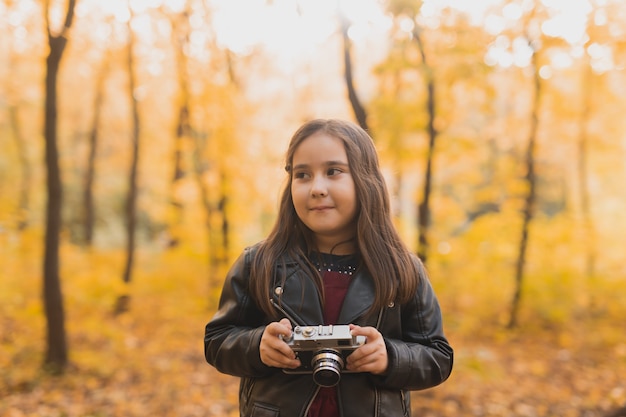 Une petite fille prend une photo avec un vieil appareil photo rétro en automne nature loisirs et passe-temps concept