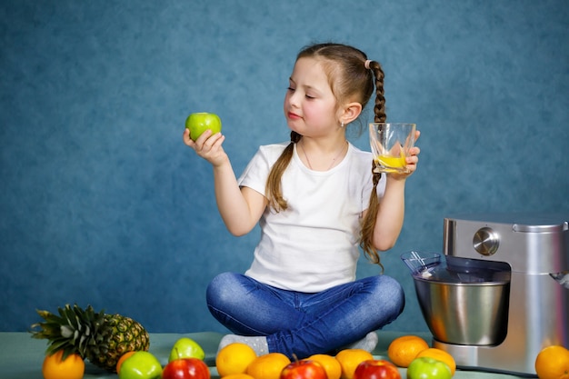 Une petite fille a pressé du jus de fruits frais de pommes et d'orange. Vitamines et alimentation saine pour les enfants.
